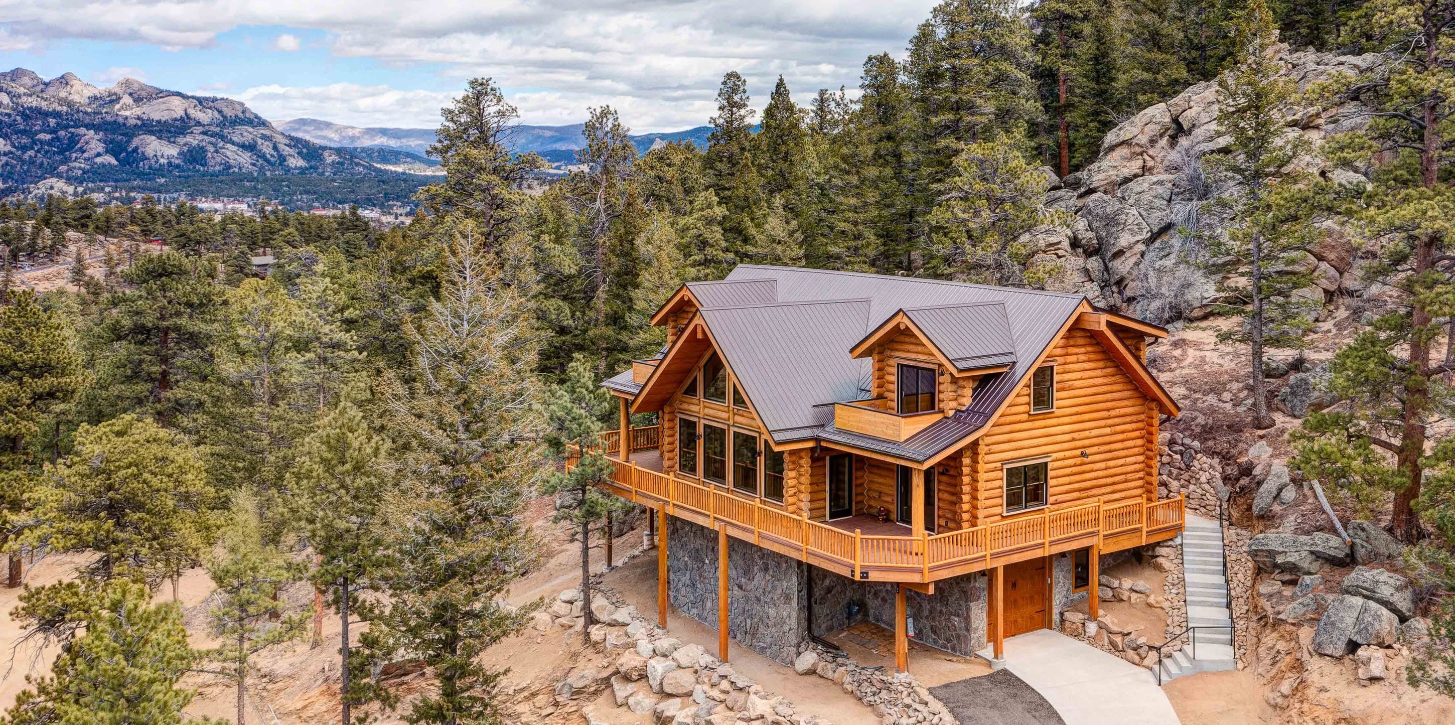 A finished Beaver custom log home in a mountain setting, full-log construction with a wraparound deck and valley views